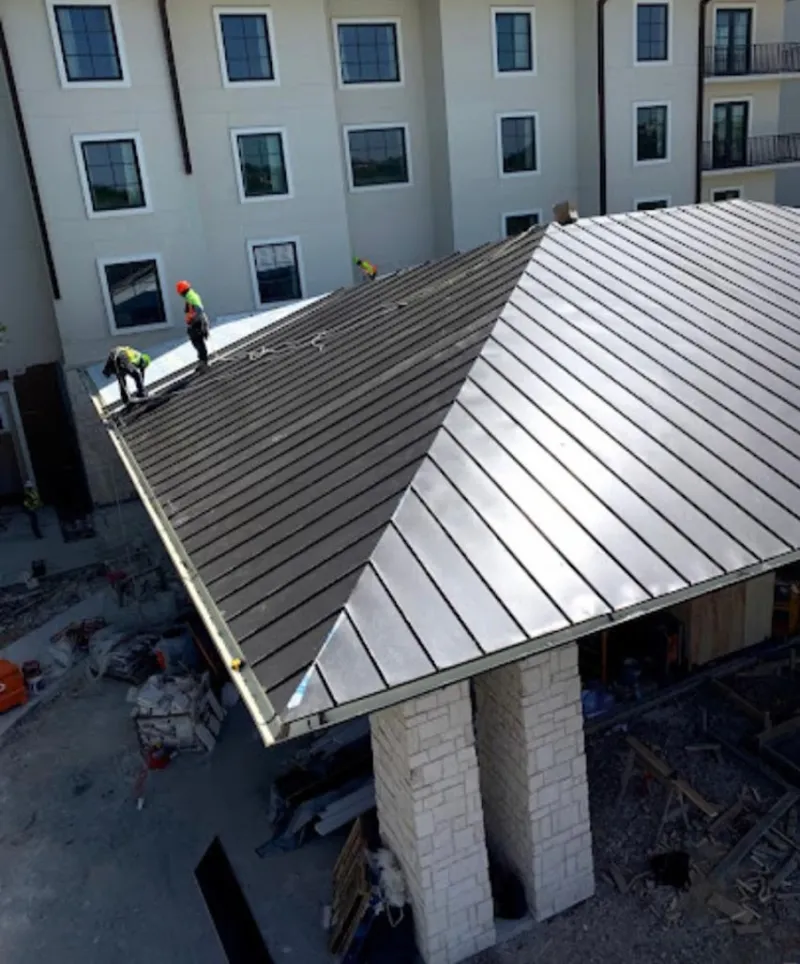 Crew installing standing seam metal roof panels on a commercial project in Boonville
